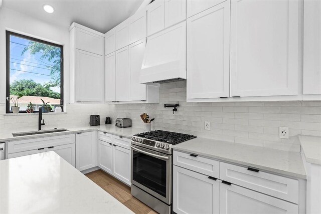 2216 Lindell Ave Unit 2, Austin, TX 78704 - kitchen featuring stainless steel range with gas stovetop, white cabinetry, backsplash, light wood-style flooring, and recessed lighting