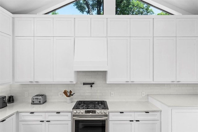 2216 Lindell Ave Unit 2, Austin, TX 78704 - kitchen featuring stainless steel range with gas stovetop, lofted ceiling, backsplash, white cabinets, and light countertops