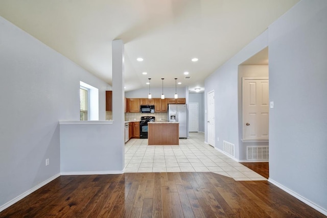 371 Bloomsbury Dr, Kyle, TX 78640 - kitchen with black appliances, light countertops, light wood-style flooring, brown cabinets, and vaulted ceiling