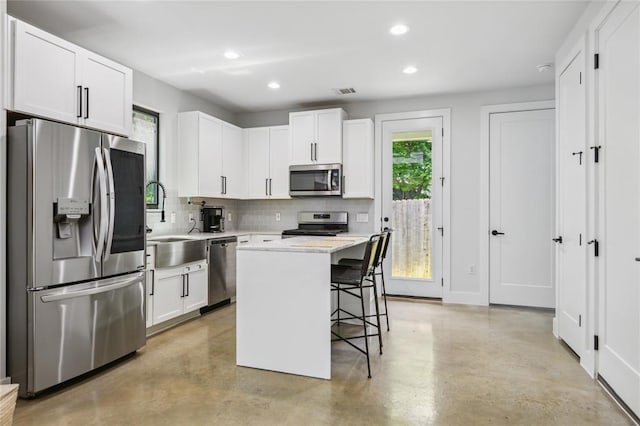 619 Hammack Dr Unit 2, Austin, TX 78752 - kitchen featuring appliances with stainless steel finishes, finished concrete floors, backsplash, a kitchen bar, and recessed lighting