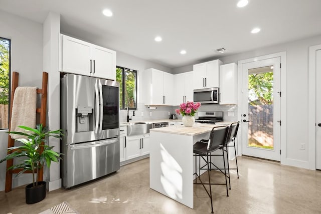 619 Hammack Dr Unit 2, Austin, TX 78752 - kitchen featuring stainless steel appliances, decorative backsplash, recessed lighting, finished concrete flooring, and a breakfast bar