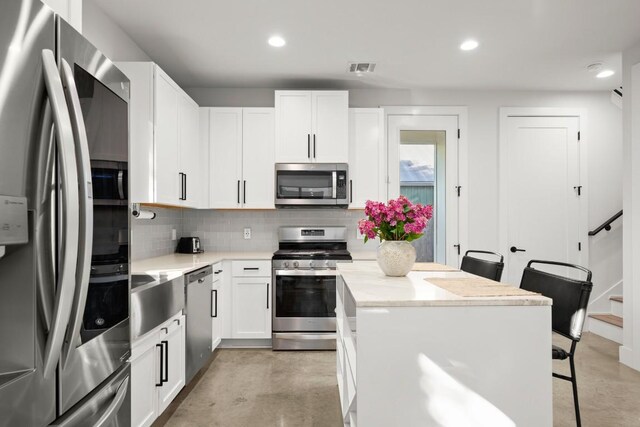 619 Hammack Dr Unit 2, Austin, TX 78752 - kitchen featuring stainless steel appliances, backsplash, white cabinets, a breakfast bar area, and recessed lighting