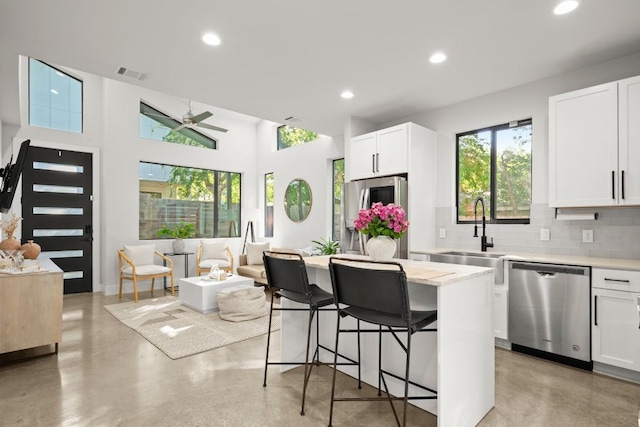 619 Hammack Dr Unit 2, Austin, TX 78752 - kitchen featuring dishwasher, tasteful backsplash, a ceiling fan, finished concrete flooring, and a breakfast bar area