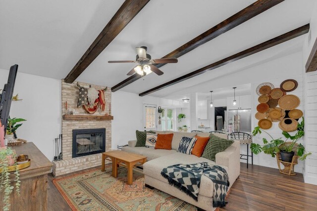 409 White Wing Way, Round Rock, TX 78664 - living room featuring a ceiling fan, wood finished floors, beam ceiling, and a brick fireplace