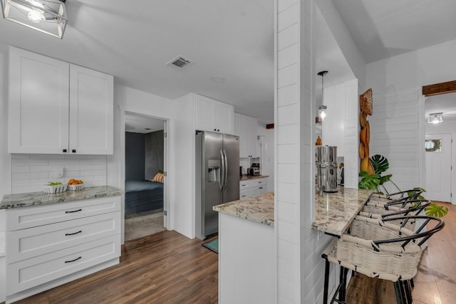 409 White Wing Way, Round Rock, TX 78664 - kitchen with stainless steel fridge, dark wood finished floors, a peninsula, decorative backsplash, and white cabinetry