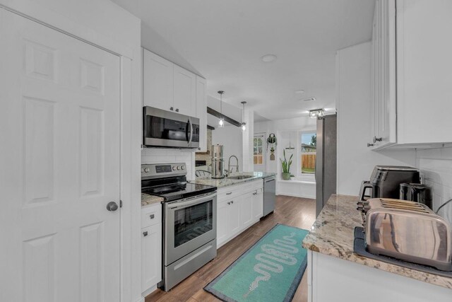 409 White Wing Way, Round Rock, TX 78664 - kitchen with stainless steel appliances, white cabinetry, light stone countertops, backsplash, and wood finished floors