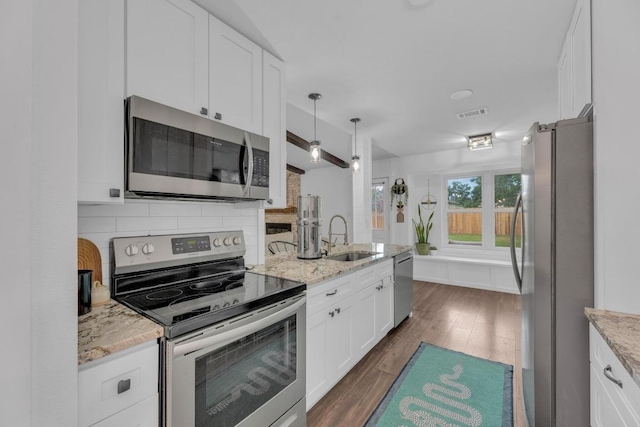 409 White Wing Way, Round Rock, TX 78664 - kitchen featuring stainless steel appliances, white cabinetry, dark wood-type flooring, backsplash, and light stone counters
