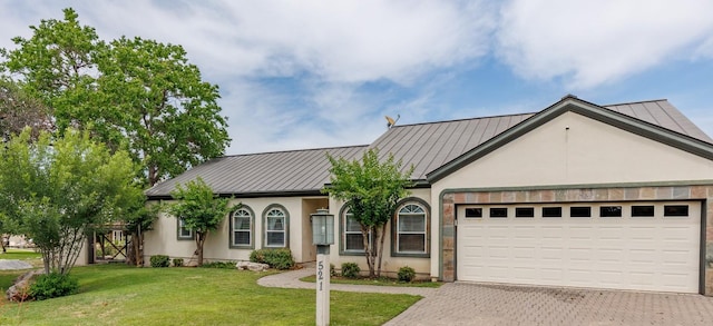 521 Lucy Ln, Horseshoe Bay, TX 78657 - view of front of house featuring decorative driveway, a front lawn, a standing seam roof, an attached garage, and stucco siding