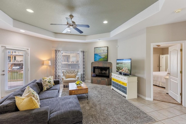 521 Lucy Ln, Horseshoe Bay, TX 78657 - living room with ceiling fan, light tile patterned floors, a raised ceiling, recessed lighting, and a tile fireplace