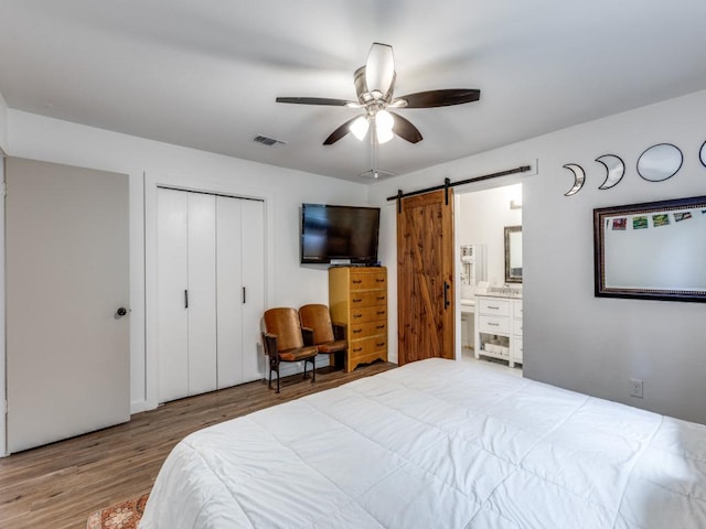 11405 Bristle Oak Trl, Austin, TX 78750 - bedroom featuring a barn door, light wood finished floors, a closet, ceiling fan, and ensuite bathroom