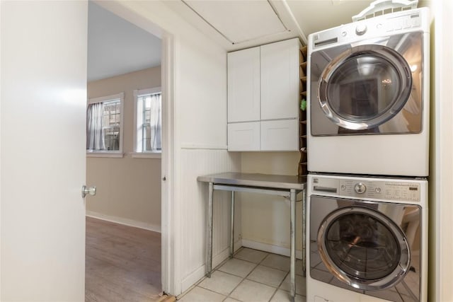 2206 Newfield Ln, Austin, TX 78703 - washroom with cabinet space, stacked washer and clothes dryer, and light wood-type flooring