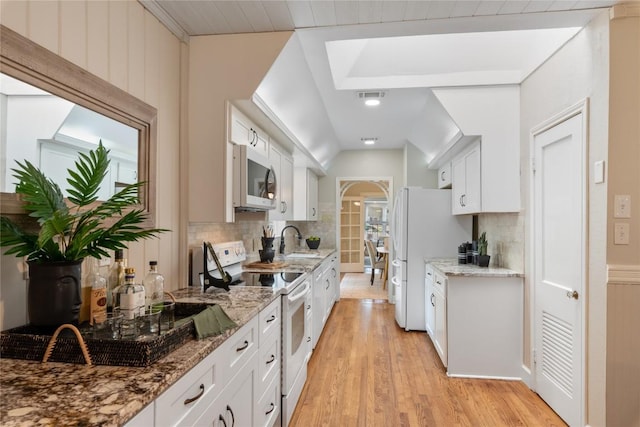 2206 Newfield Ln, Austin, TX 78703 - kitchen with white appliances, decorative backsplash, light wood-style floors, and white cabinets