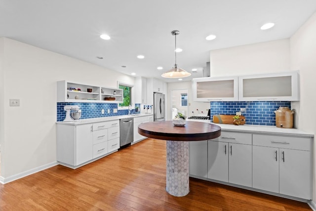 7710 Shoal Creek Blvd, Austin, TX 78757 - kitchen with stainless steel appliances, tasteful backsplash, light countertops, light wood finished floors, and white cabinets