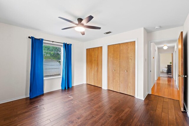 7710 Shoal Creek Blvd, Austin, TX 78757 - unfurnished bedroom featuring two closets, dark wood-type flooring, and ceiling fan