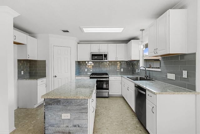 1213 Pathfinder Way, Round Rock, TX 78665 - kitchen featuring appliances with stainless steel finishes, backsplash, white cabinets, light stone counters, and decorative light fixtures