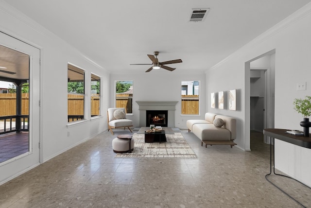 1213 Pathfinder Way, Round Rock, TX 78665 - living room featuring a ceiling fan, crown molding, healthy amount of natural light, and a warm lit fireplace