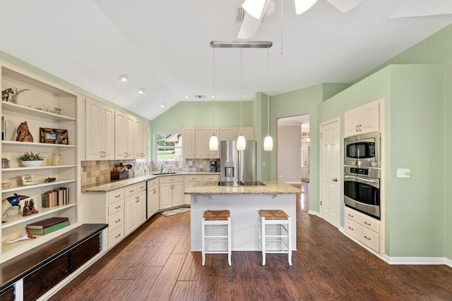 1011 Windmill Rd, Dripping Springs, TX 78620 - kitchen featuring appliances with stainless steel finishes, dark wood-type flooring, vaulted ceiling, a center island, and a breakfast bar