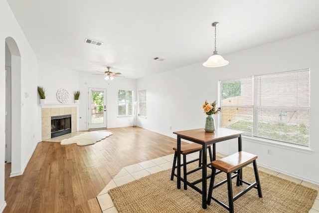 141 Ashwood N, Kyle, TX 78640 - dining room with arched walkways, a ceiling fan, a fireplace, and light wood-style floors