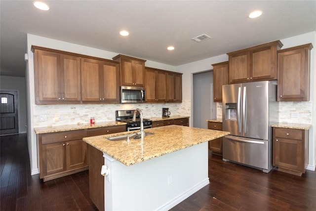 6007 Agostino Cv, Round Rock, TX 78665 - kitchen with stainless steel appliances, dark wood-type flooring, an island with sink, backsplash, and light stone counters
