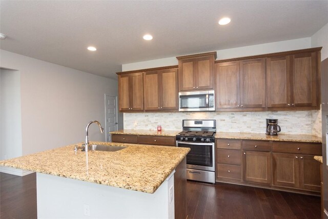 6007 Agostino Cv, Round Rock, TX 78665 - kitchen featuring appliances with stainless steel finishes, dark wood-type flooring, decorative backsplash, light stone countertops, and recessed lighting