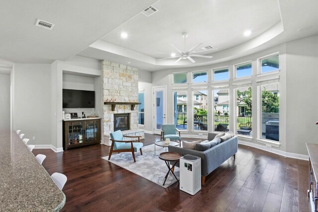 1720 Boscello Ct, Leander, TX 78641 - living area featuring a tray ceiling, dark wood-style flooring, a ceiling fan, a fireplace, and recessed lighting