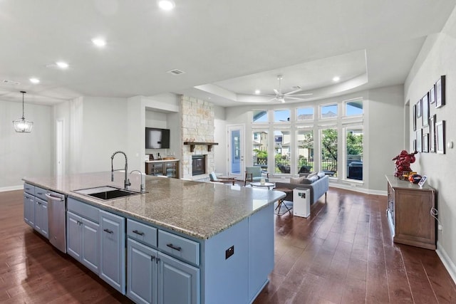 1720 Boscello Ct, Leander, TX 78641 - kitchen with open floor plan, recessed lighting, stainless steel dishwasher, a tray ceiling, and a fireplace