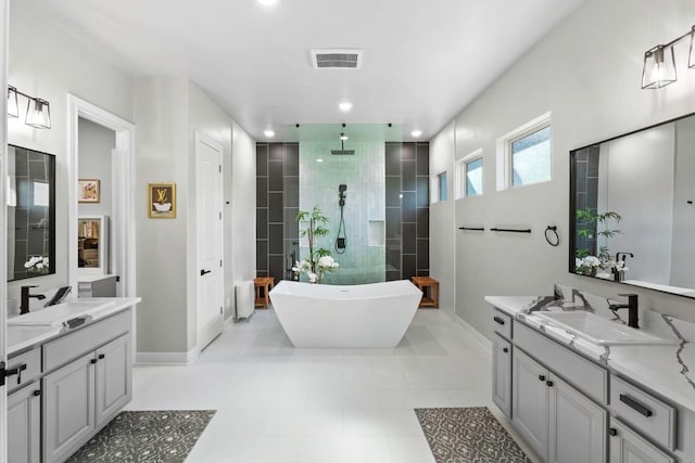 1720 Boscello Ct, Leander, TX 78641 - full bathroom featuring a walk in shower, two vanities, a freestanding bath, tile patterned flooring, and recessed lighting