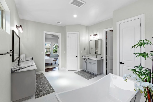 1720 Boscello Ct, Leander, TX 78641 - ensuite bathroom featuring two vanities, a soaking tub, and recessed lighting