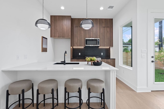 54 Robert T Martinez Jr St, Austin, TX 78702 - kitchen featuring stainless steel microwave, modern cabinets, a kitchen breakfast bar, tasteful backsplash, and recessed lighting