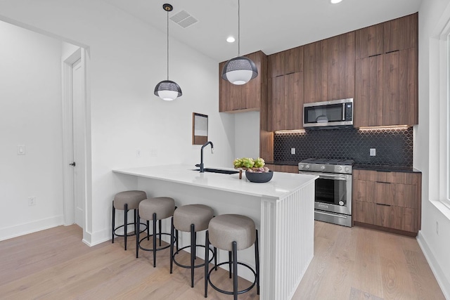54 Robert T Martinez Jr St, Austin, TX 78702 - kitchen featuring appliances with stainless steel finishes, modern cabinets, a kitchen breakfast bar, light wood-style floors, and recessed lighting