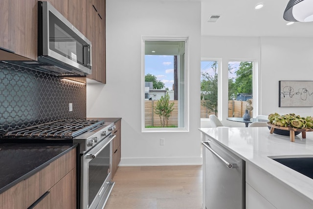 54 Robert T Martinez Jr St, Austin, TX 78702 - kitchen featuring stainless steel appliances, modern cabinets, light wood finished floors, decorative backsplash, and recessed lighting