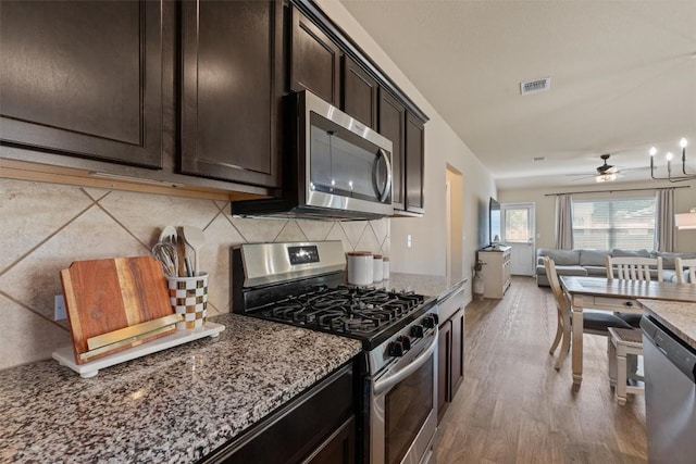 3402 Tilmon Ln, Austin, TX 78725 - kitchen with stainless steel appliances, light stone counters, open floor plan, decorative backsplash, and dark brown cabinets