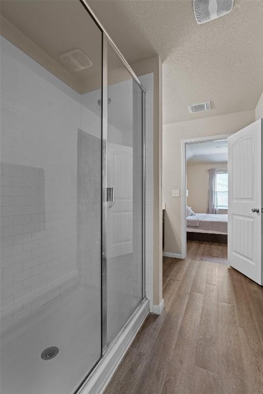 3402 Tilmon Ln, Austin, TX 78725 - full bathroom featuring ensuite bath, a stall shower, wood finished floors, and a textured ceiling