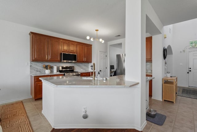 4201 Veiled Falls Dr, Pflugerville, TX 78660 - kitchen with stainless steel appliances, backsplash, light tile patterned flooring, and brown cabinets