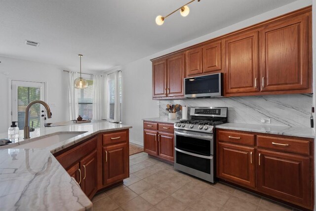 4201 Veiled Falls Dr, Pflugerville, TX 78660 - kitchen featuring stainless steel appliances, tasteful backsplash, light stone countertops, pendant lighting, and brown cabinetry
