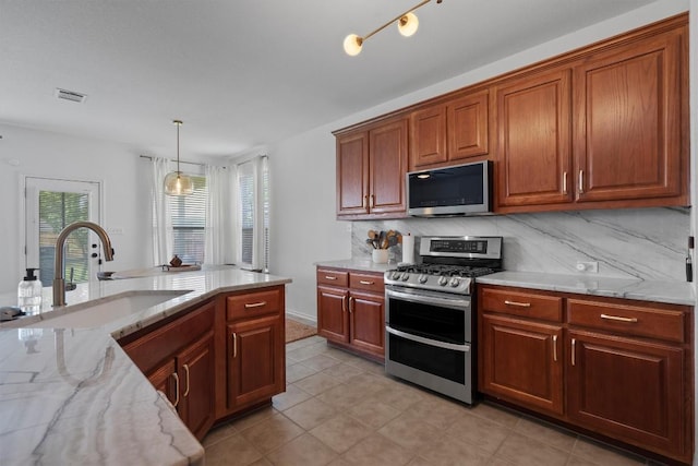 4201 Veiled Falls Dr, Pflugerville, TX 78660 - kitchen featuring appliances with stainless steel finishes, decorative backsplash, light stone countertops, pendant lighting, and brown cabinetry