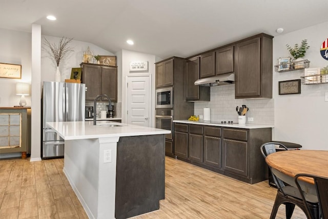 1703 Omaha Dr, Lago Vista, TX 78645 - kitchen featuring appliances with stainless steel finishes, under cabinet range hood, dark brown cabinets, light countertops, and tasteful backsplash
