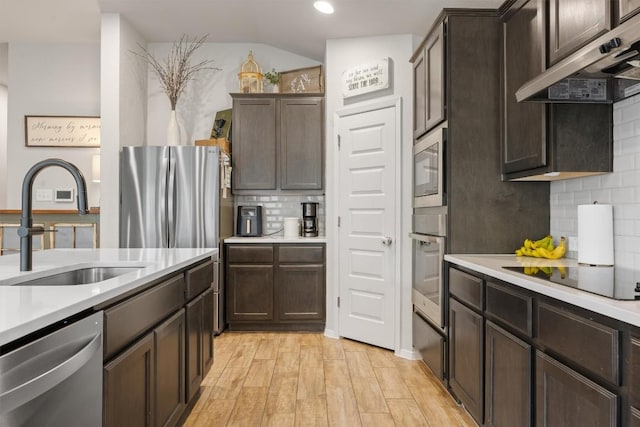 1703 Omaha Dr, Lago Vista, TX 78645 - kitchen with stainless steel appliances, under cabinet range hood, decorative backsplash, light wood finished floors, and light countertops