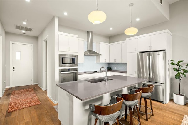 5921 Hiline Rd Unit 2404, Austin, TX 78734 - kitchen featuring stainless steel appliances, wall chimney range hood, light wood-style floors, backsplash, and recessed lighting