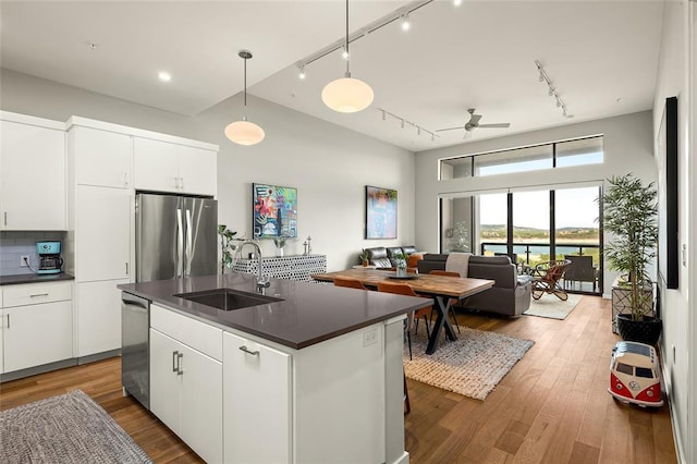 5921 Hiline Rd Unit 2404, Austin, TX 78734 - kitchen featuring appliances with stainless steel finishes, dark countertops, rail lighting, white cabinetry, and wood finished floors