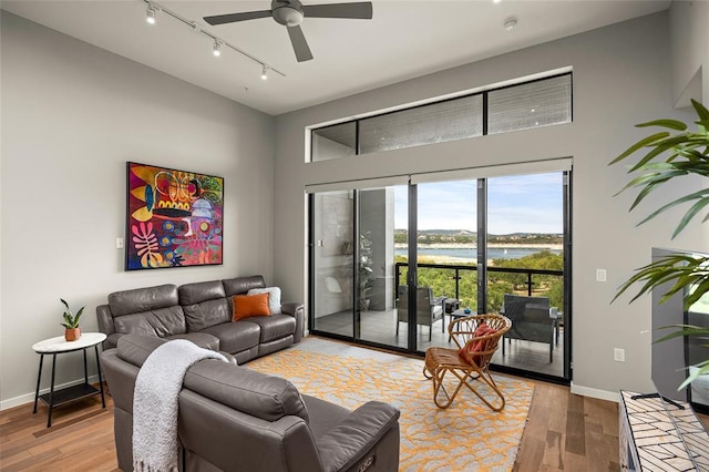 5921 Hiline Rd Unit 2404, Austin, TX 78734 - living room featuring a water view, rail lighting, light wood finished floors, ceiling fan, and a towering ceiling