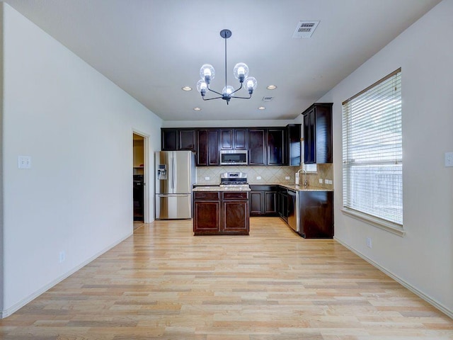 11509 Timber Heights Dr, Austin, TX 78754 - kitchen featuring stainless steel appliances, a chandelier, light countertops, light wood-style floors, and decorative backsplash