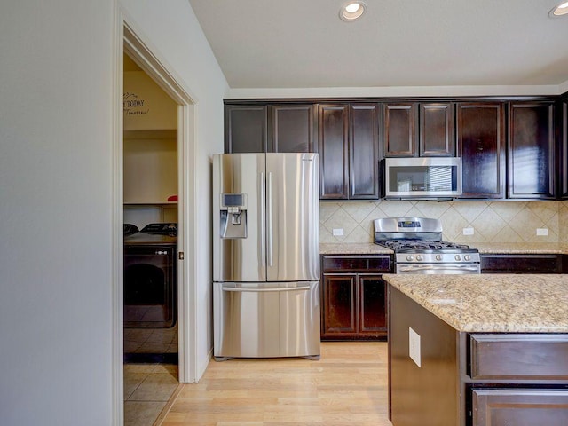 11509 Timber Heights Dr, Austin, TX 78754 - kitchen featuring stainless steel appliances, light stone counters, dark brown cabinetry, tasteful backsplash, and light wood finished floors