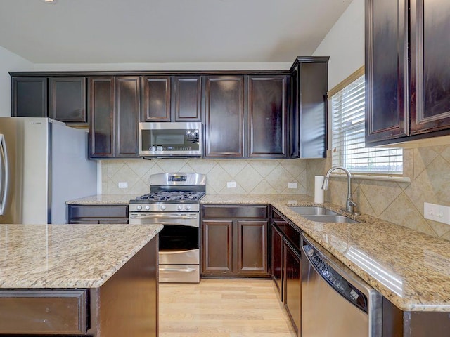11509 Timber Heights Dr, Austin, TX 78754 - kitchen featuring appliances with stainless steel finishes, light stone countertops, light wood-style flooring, and dark brown cabinets