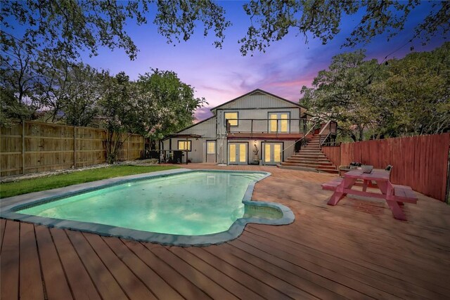 15507 Enid Dr, Austin, TX 78734 - pool at dusk featuring french doors, a wooden deck, stairs, and a fenced backyard
