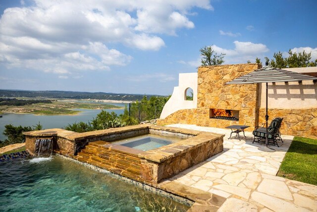 908 Watercliffe Dr, Lago Vista, TX 78645 - view of pool featuring an outdoor stone fireplace, an in-ground hot tub, a patio, and a water view