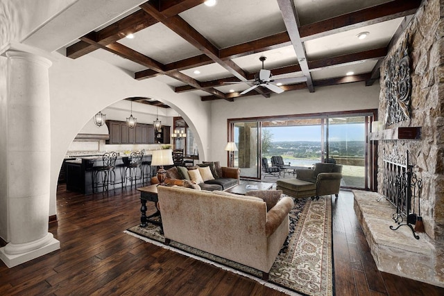 908 Watercliffe Dr, Lago Vista, TX 78645 - living room with arched walkways, a ceiling fan, dark wood-style floors, a fireplace, and beamed ceiling
