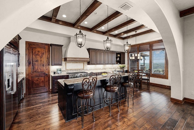 908 Watercliffe Dr, Lago Vista, TX 78645 - kitchen featuring dark wood-style floors, decorative backsplash, a breakfast bar area, beamed ceiling, and dark brown cabinetry