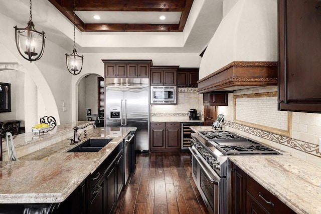 908 Watercliffe Dr, Lago Vista, TX 78645 - kitchen featuring custom exhaust hood, built in appliances, a tray ceiling, dark wood finished floors, and decorative backsplash