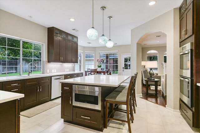 10309 Van Winkle Ct, Austin, TX 78739 - kitchen with dishwashing machine, stainless steel double oven, light countertops, arched walkways, and recessed lighting